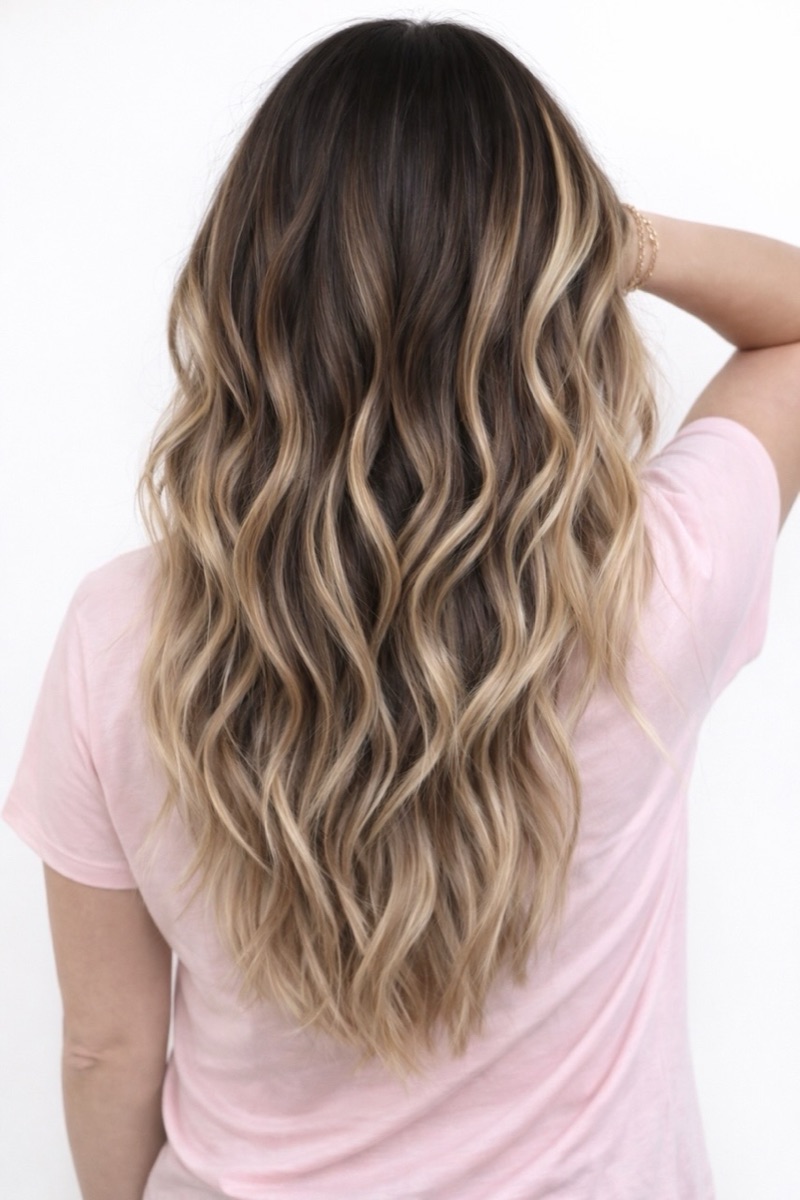 Dark brown to blonde balayage on long wavy hair at Moxi Hair Studio